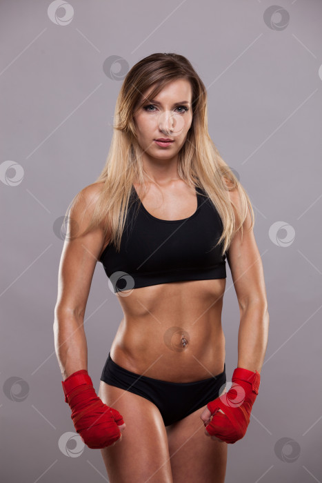Скачать спортивная девушка позирует в красных повязках, изолированная на сером фоне боксерского бойца кикбоксера фотосток Ozero