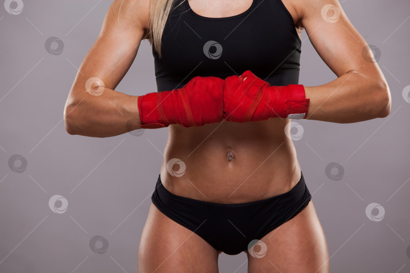 Скачать Крупный план спортивной девушки, позирующей в красных повязках, изолированной на сером фоне боксерского бойца кикбоксинга фотосток Ozero