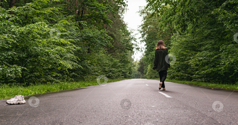 Скачать Молодая девушка идет по дороге в лесу фотосток Ozero