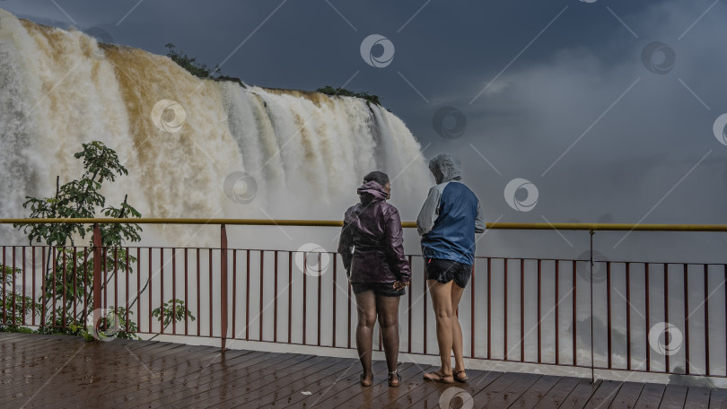 Скачать Два человека стоят на смотровой площадке у водопада. фотосток Ozero