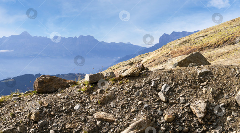 Скачать Горный склон с крупными камнями и мелкой галькой. Горный хребет на заднем плане. Панорама гор. фотосток Ozero