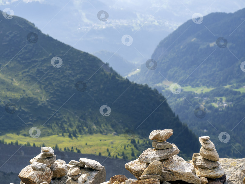 Скачать На краю обрыва сложены пирамиды из камней. На заднем плане видны горы и леса. Естественный горный ландшафт. фотосток Ozero
