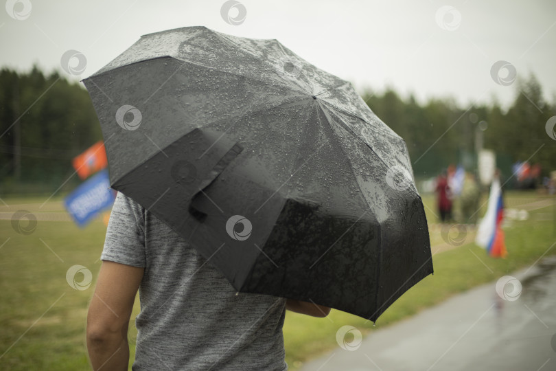 Скачать Черный зонт во время дождя. Большой зонт в плохую погоду. Мужчина на улице в пасмурный день. фотосток Ozero