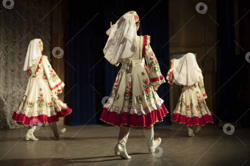 Скачать Девушки танцуют в народных костюмах. На сцене. Народный танец. Просторные платья. фотосток Ozero