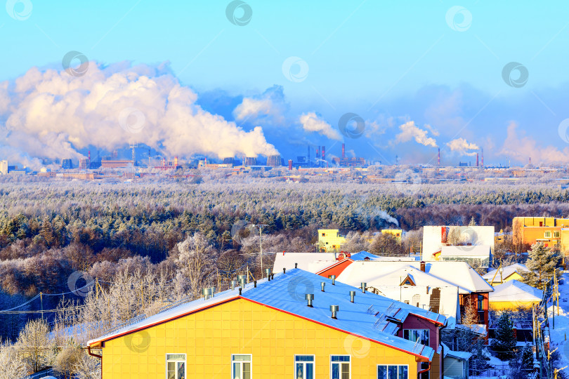 Скачать Городской пейзаж - вид жилых многоквартирных домов в городе на фоне заводских труб, выбрасывающих токсичный дым в атмосферу. Загрязнение воздуха из дымоходов сталелитейных заводов. Разрушение озонового слоя. фотосток Ozero