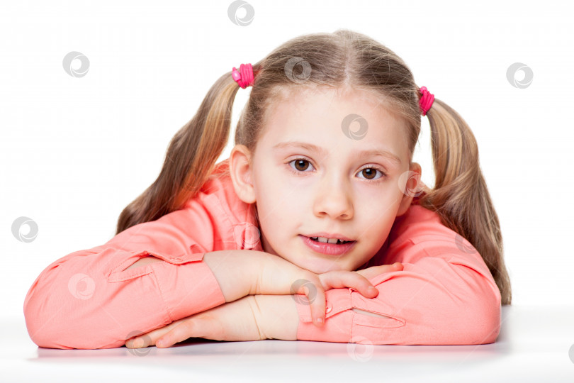 Скачать Портрет милой маленькой девочки с головой на руках, сидящей за столом, изолированной на простом фоне фотосток Ozero
