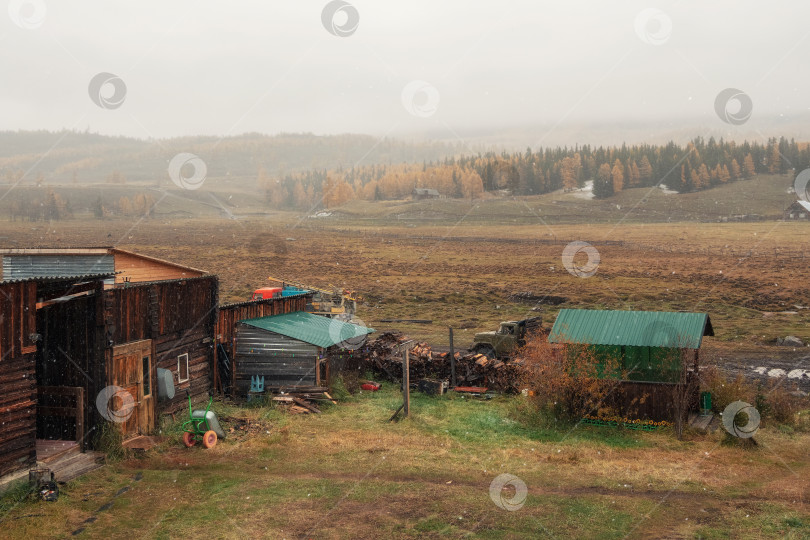 Скачать Ностальгический сельский пейзаж поздней осени. Осенняя ферма на Алтае. Идет снег фотосток Ozero