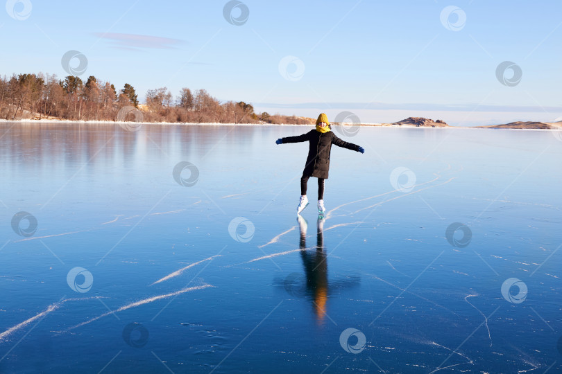 Скачать Молодая спортивная девушка катается на коньках по прозрачному льду замерзшего озера Байкал. фотосток Ozero
