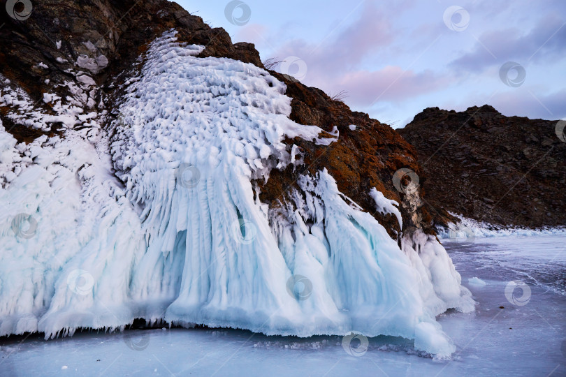 Скачать Скалы покрыты снегом и сосульками. Замерзшее озеро Байкал на закате фотосток Ozero