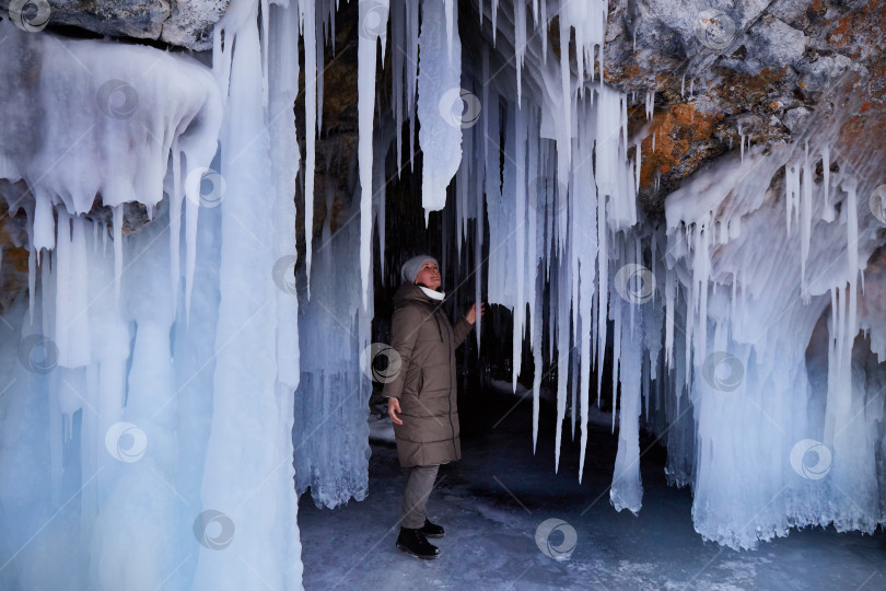 Скачать Женщина исследует огромные сосульки в ледяной пещере острова Олтрек. Зимнее путешествие по замерзшему озеру Байкал фотосток Ozero