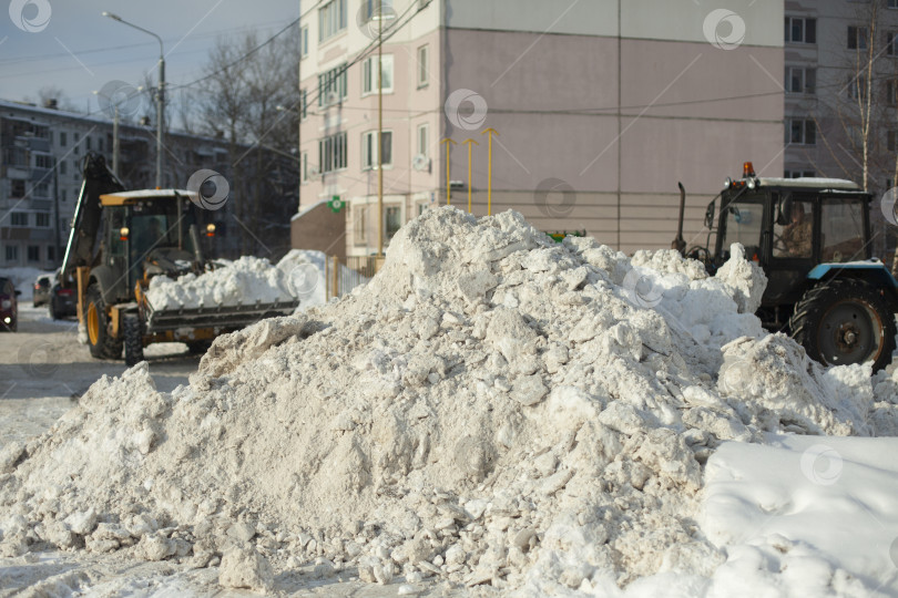 Скачать Уборка снега на улице. Бульдозер убирает снег в городе. Большие глыбы снега. фотосток Ozero