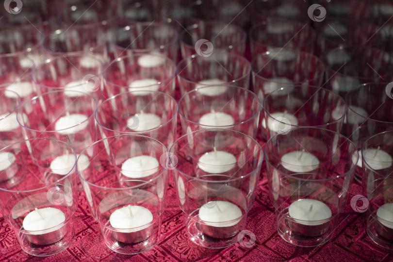 Скачать Свечи на столе. Круглые парафиновые свечи. Ряды прозрачных бокалов. фотосток Ozero