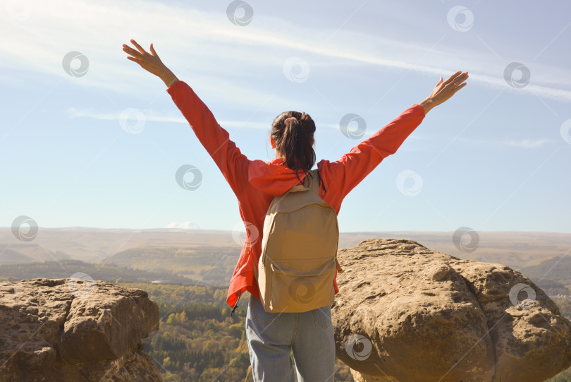 Скачать Активная молодая женщина с рюкзаком отправляется в поход по горам с поднятыми вверх руками. фотосток Ozero