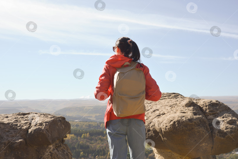 Скачать Активная молодая женщина с рюкзаком отправляется в поход по горам, наслаждаясь панорамными видами. фотосток Ozero