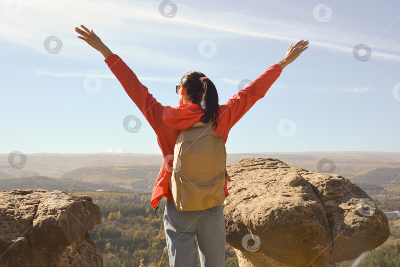 Скачать Активная молодая женщина с рюкзаком, идущая в поход по горам с поднятыми вверх руками фотосток Ozero
