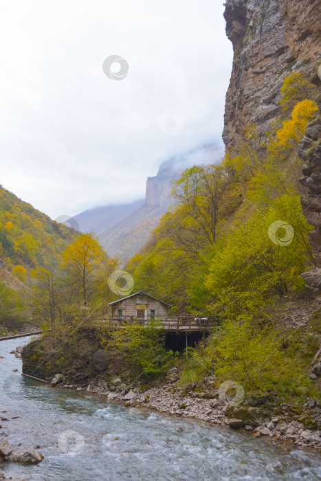 Скачать Небольшой домик у горной реки и подножия туманных гор. Северный Кавказ, Россия. фотосток Ozero