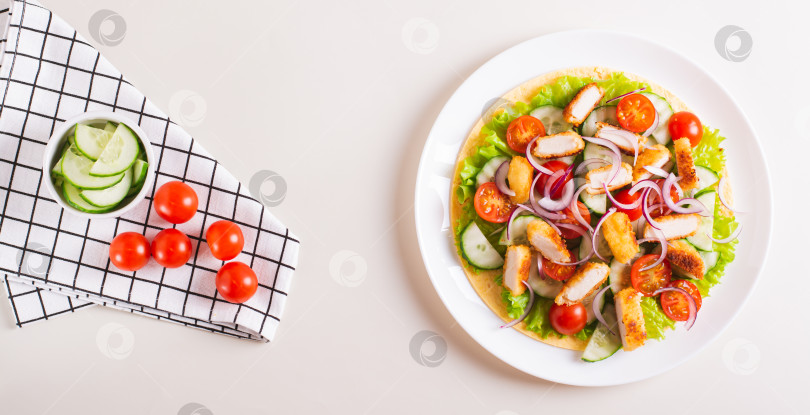 Скачать Тортилья с наггетсами, овощами и листьями салата на тарелке на столешнице посмотреть веб-баннер фотосток Ozero
