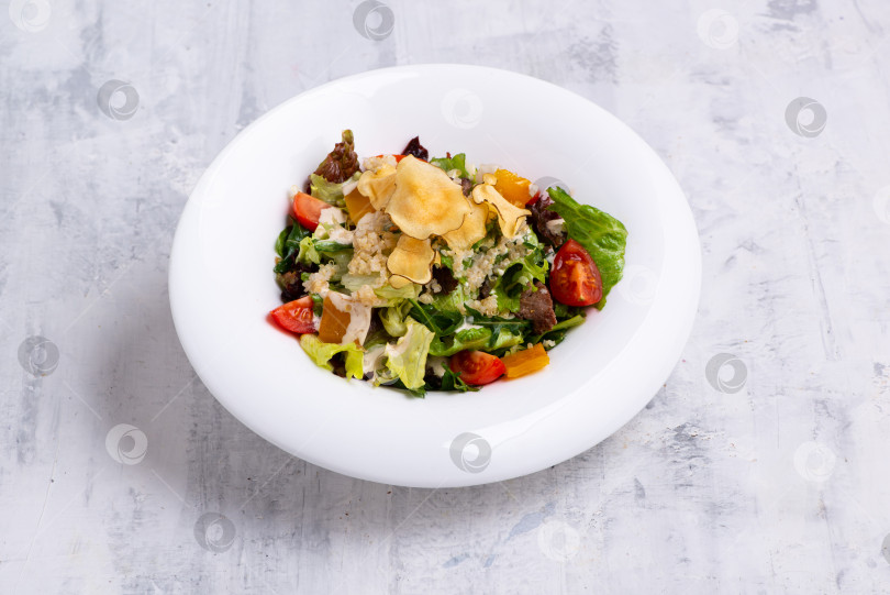 Скачать Снимок крупным планом вкусного салата "Цезарь", поданного в белом блюде на белой мраморной поверхности фотосток Ozero