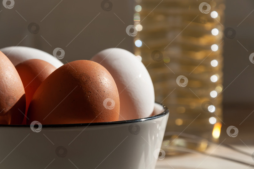 Скачать Яйца в керамической чашке крупным планом. Готовим на кухне. Белые и коричневые яйца. Бутылка масла крупным планом. Венчик для взбивания теста и сливок. фотосток Ozero