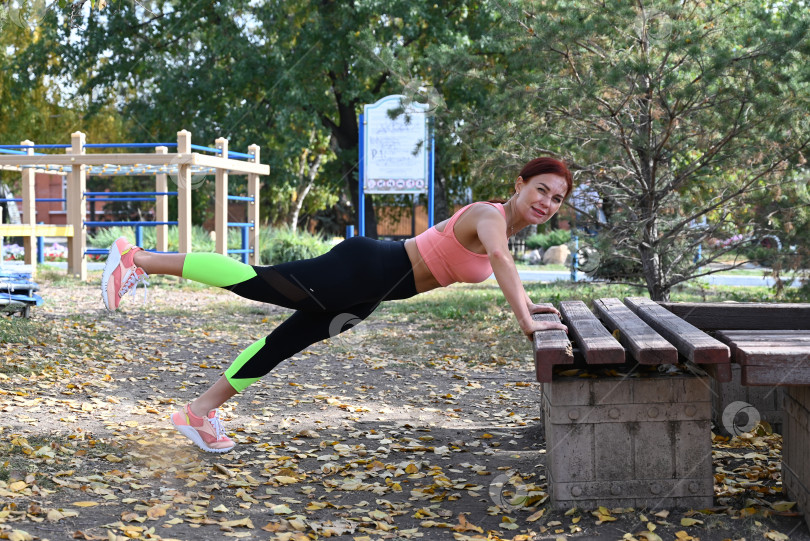 Скачать Спортсмен в удобной спортивной одежде. Фитнес на открытом воздухе в городе. Здоровый образ жизни. Тренер занимается на улице. Уверенная в себе женщина делает тренировку. фотосток Ozero