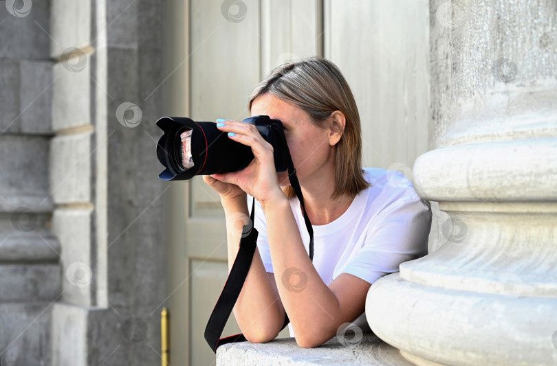 Скачать женщина-фотограф с фотоаппаратом в руках прогуливается по улицам города фотосток Ozero