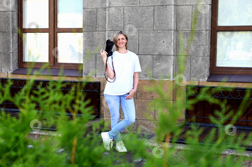 Скачать женщина-фотограф с фотоаппаратом в руках прогуливается по улицам города фотосток Ozero
