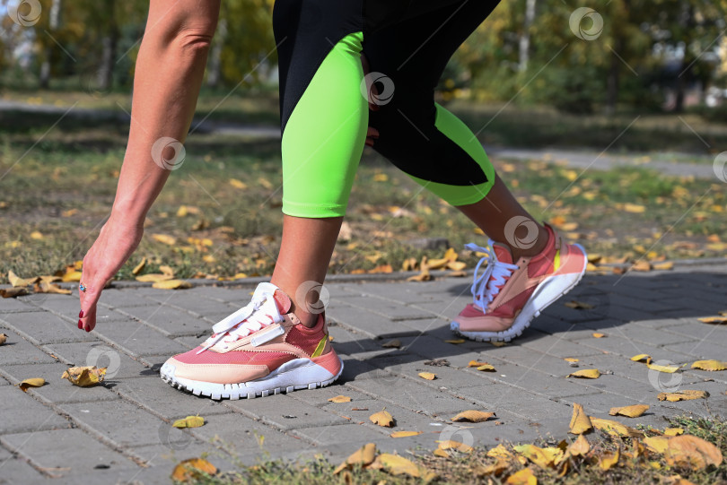 Скачать Спортсмен в удобной спортивной одежде. Фитнес на открытом воздухе в городе. Здоровый образ жизни. Тренер занимается на улице. Уверенная в себе женщина делает тренировку. фотосток Ozero