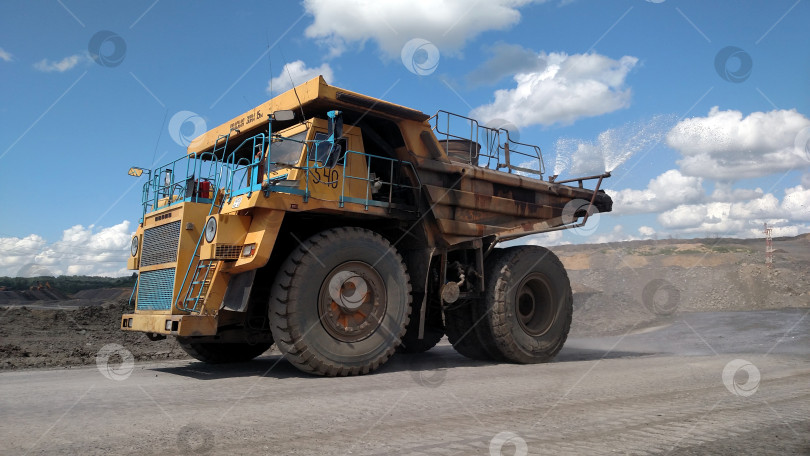 Скачать Поливалка технологических дорог на территории карьерного добывающего предприятия в ясный солнечный день во время работы фотосток Ozero