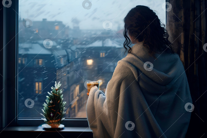 Скачать Молодая женщина в задумчивом настроении пьет кофе у окна и любуется зимним городом фотосток Ozero