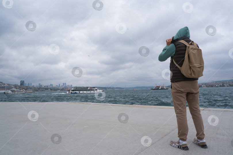 Скачать Турист мужского пола фотографирует пейзаж на набережной Босфора в Стамбуле, Турция, на память. фотосток Ozero