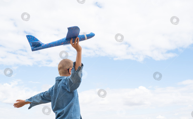 Скачать Вид сзади на ребенка, мальчика с самолетом, мечтающего о путешествии летом на природе на фоне голубого неба фотосток Ozero