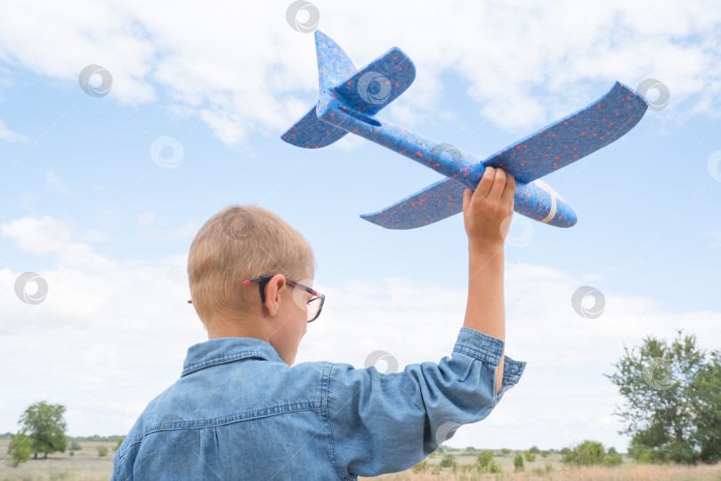 Скачать Портрет счастливого ребенка, играющего с игрушечным самолетиком на фоне голубого неба в открытом поле фотосток Ozero