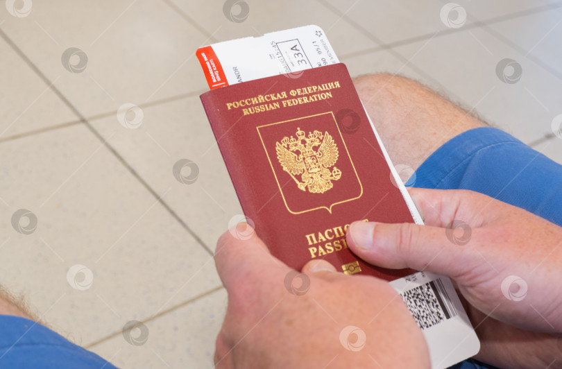 Скачать Мужские руки, держащие паспорт с билетами на самолет, вид сверху фотосток Ozero
