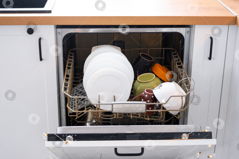 Скачать Много грязной посуды в посудомоечной машине на праздничной кухне. Помощь хозяйке, экономия и экология. Уборка на кухне к праздникам Рождества и Нового года, после застолья и гостей фотосток Ozero