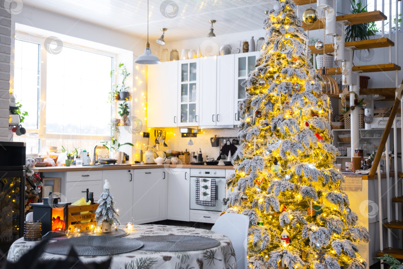 Скачать Праздничный рождественский декор на белой кухне, современный деревенский интерьер со снежной елкой и гирляндами. Новый год, рождественское настроение, уютный дом, металлическая модульная лестница. Общий план фотосток Ozero