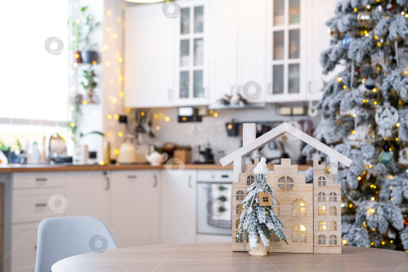 Скачать Ключ на рождественской елке и крошечный домик в уютном доме с рождественским декором на столе праздничной белой кухни. Подарок на Новый год. Страхование, переезд в новый дом, ипотека, аренда и покупка недвижимости фотосток Ozero