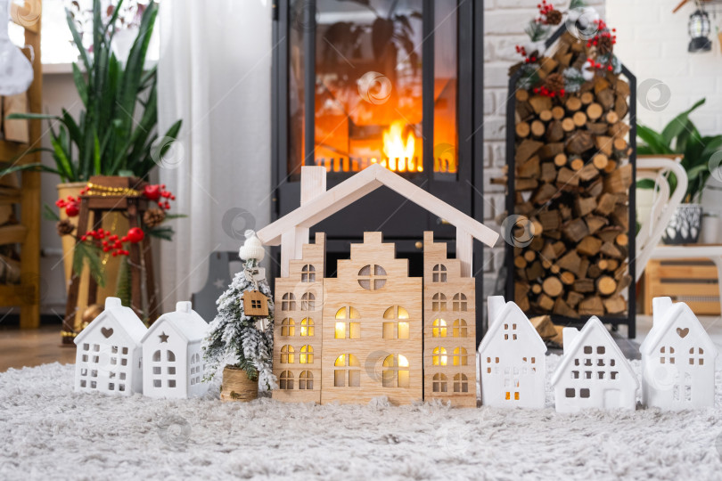 Скачать Ключ на рождественской елке и крошечный домик в уютном доме с рождественским декором возле горящей печи-камина. Подарок на Новый год. Страхование, переезд в новый дом, ипотека, аренда и недвижимость фотосток Ozero