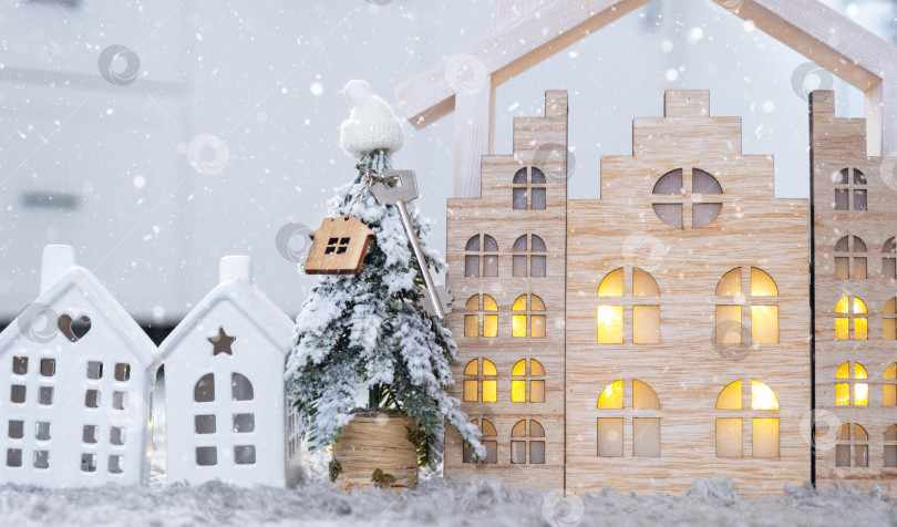 Скачать Ключ на рождественской елке и крошечный домик в уютном доме с рождественским декором на столе праздничной белой кухни. Подарок на Новый год. Страхование, переезд в новый дом, ипотека, аренда и недвижимость фотосток Ozero