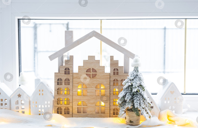 Скачать Уютный рождественский декор крошечного домика небольшого размера на подоконнике со снегом за окном. Подарок на Новый год. Страхование, переезд в новый дом, ипотека, аренда и покупка недвижимости фотосток Ozero