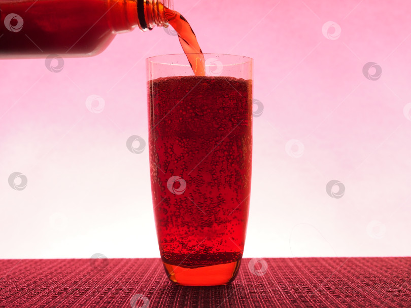 Скачать В прозрачном бокале, наполненном темным газированным напитком. Фотография на розовом фоне. фотосток Ozero