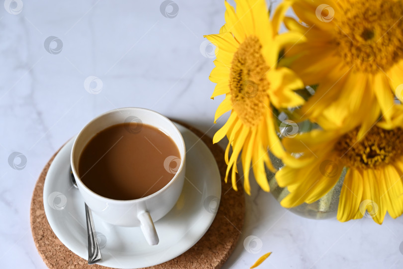 Скачать Утренний кофе. Уютная композиция: чашка кофе на раскрытой книге, синий свитер и цветы подсолнуха на бетонном фоне. Концепция натюрморта. Пространство для копирования. фотосток Ozero