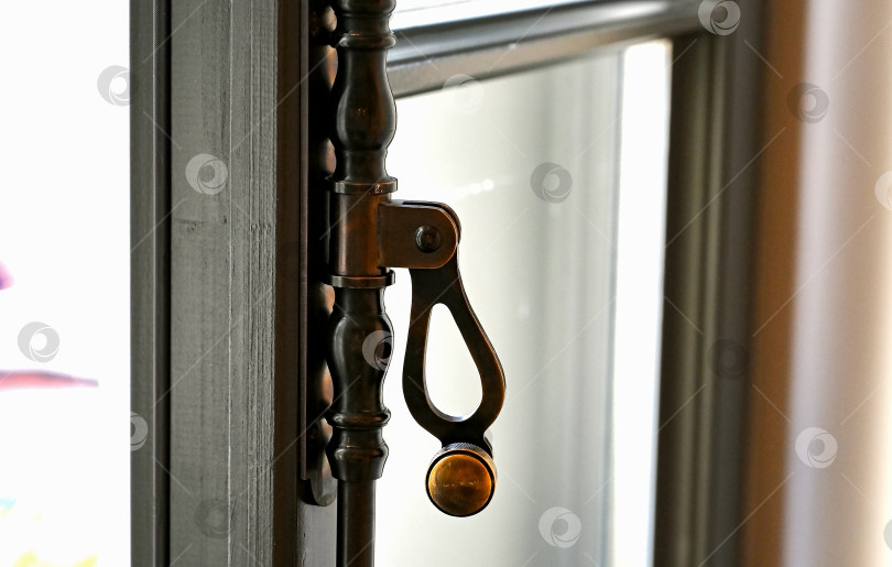 Скачать Крупный план старинного металлического оконного рычага. Латунная ручка на старом деревянном окне фотосток Ozero