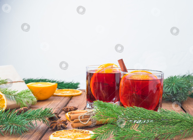 Скачать Рождественский глинтвейн на деревянном фоне со специями, еловыми ветками и сушеным апельсином. фотосток Ozero