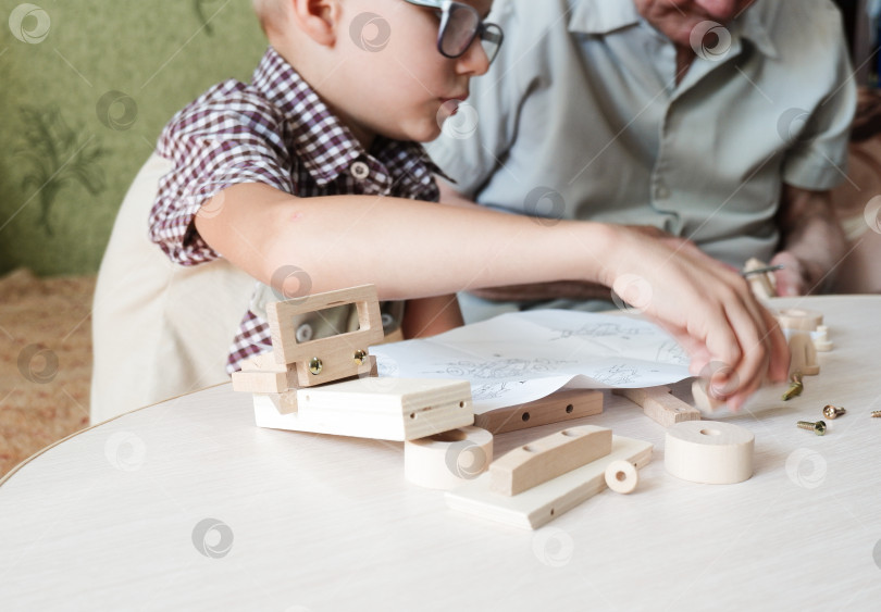 Скачать дедушка и маленький мальчик ремонтируют деревянную модель автомобиля. Концепция взаимоотношений детей и пожилых людей. Тренировка навыков фотосток Ozero