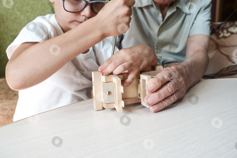 Скачать Дедушка и внук собирают дома деревянную игрушечную машинку с помощью отверток. Отношения между поколениями фотосток Ozero