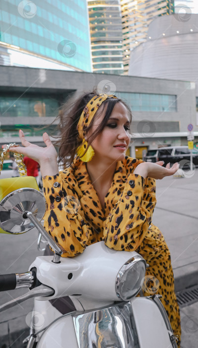 Скачать Портрет модно одетой счастливой женщины, позирующей для фотосессии на мопеде фотосток Ozero