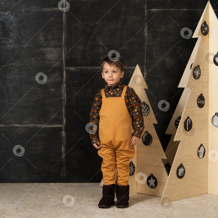Скачать маленький мальчик рядом с декоративными рождественскими елками фотосток Ozero