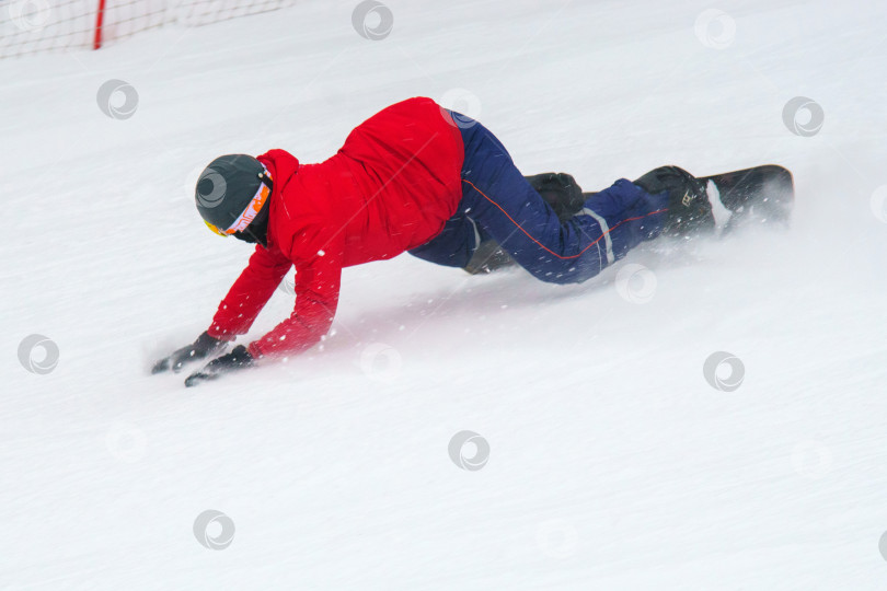 Скачать Человек в красной куртке и черном шлеме катается на сноуборде. Выборочный фокус фотосток Ozero