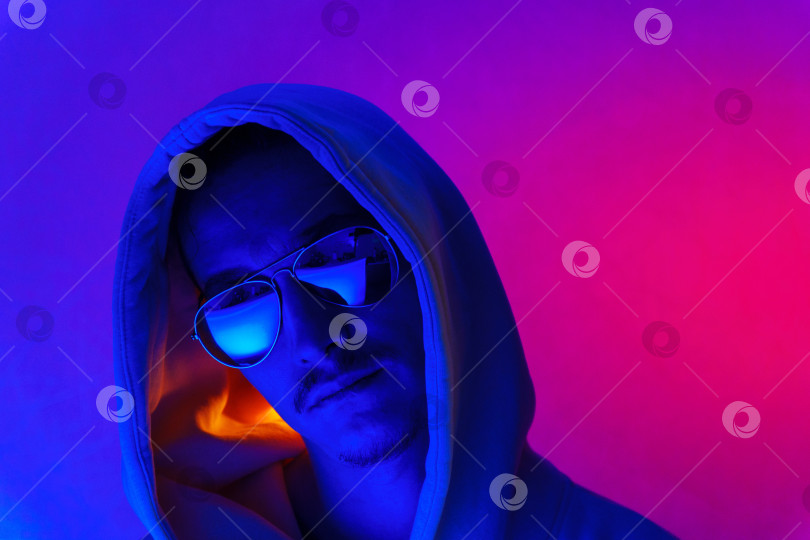 Скачать Портрет молодого человека в профиль в студии. Мужчина-модель в ярких неоновых огнях позирует на фиолетовом фоне фотосток Ozero