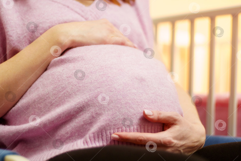 Скачать Женщина держится за живот, сидя на стуле. Беременная женщина ожидает ребенка. Избирательный фокус фотосток Ozero